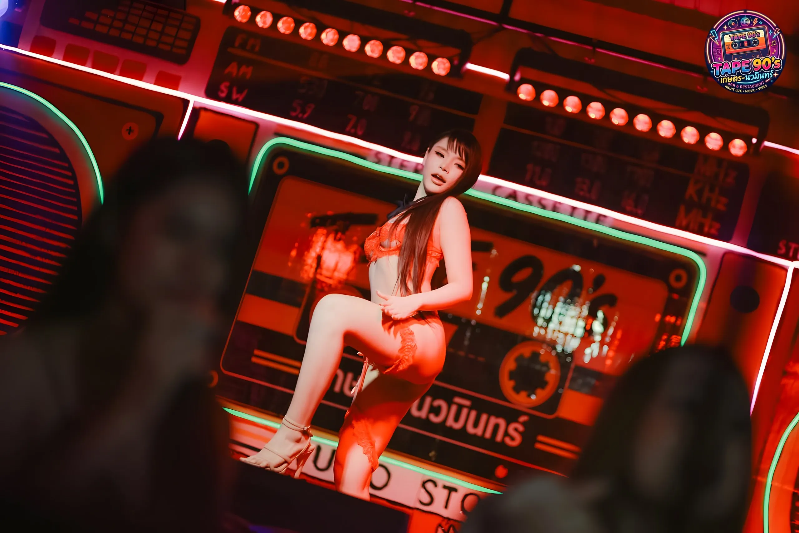 Vũ công trên sân khấu đèn neon đỏ trong quán