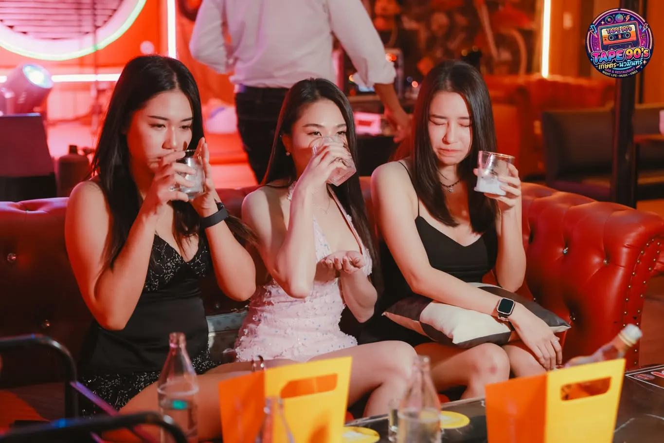 Ba cô gái nâng ly trên ghế da đỏ
